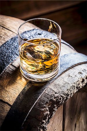 A glass of whiskey with ice on an old wooden barrel Stock Photo - Premium Royalty-Free, Code: 659-08904762