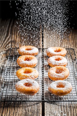 Freshly baked doughnuts being dusted with icing sugar Stock Photo - Premium Royalty-Free, Code: 659-08904777