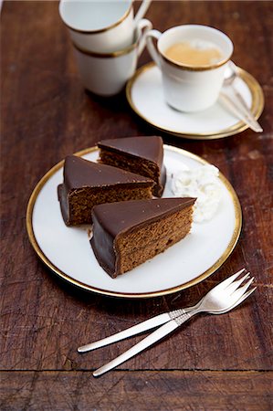 pictures of chocolate gateau cake - Sachertorte (rich Austrian chocolate cake) with whipped cream and a cup of coffee Stock Photo - Premium Royalty-Free, Code: 659-08905010