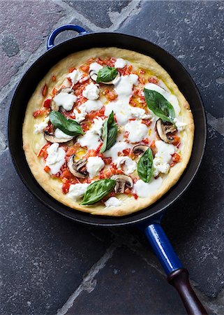 Pizza with mushrooms, tomatoes, basil and buffalo mozzarella in a cast iron pan Stock Photo - Premium Royalty-Free, Code: 659-08905020