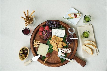 A cheesebaord with fresh fruit, sauces, nuts, capers, breadsticks, crackers and white bread Stock Photo - Premium Royalty-Free, Code: 659-08905101