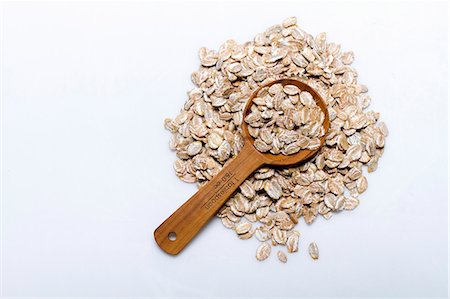 A pile of rye flakes with a wooden spoon on a white surface Stock Photo - Premium Royalty-Free, Code: 659-08905247
