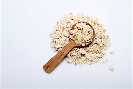 simsearch:659-03522742,k - A pile of oats with a wooden spoon on a white surface Photographie de stock - Premium Libres de Droits, Code: 659-08905242