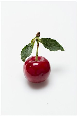 A sour cherry with a stem and leaves on a white surface Stockbilder - Premium RF Lizenzfrei, Bildnummer: 659-08905258
