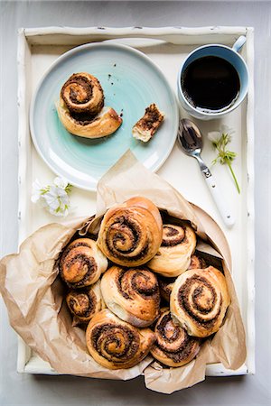 Sweet yeast swirls with a brown sugar, cinnamon and pecan nut filling on a tray with coffee Stock Photo - Premium Royalty-Free, Code: 659-08905450