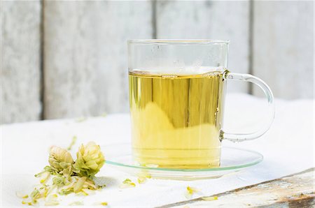Hot tea in a glass cup next to dried hops on a wooden table Stock Photo - Premium Royalty-Free, Code: 659-08905729