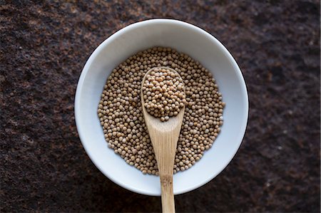 simsearch:659-07028491,k - Mustard seeds with a wooden spoon in a bowl (seen from above) Foto de stock - Sin royalties Premium, Código: 659-08905966