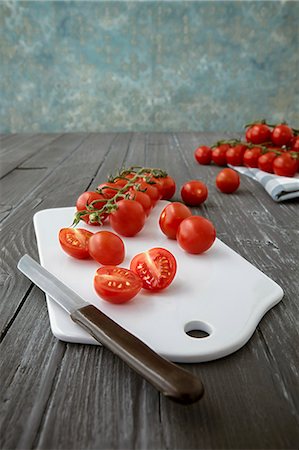 simsearch:659-08896342,k - Cherry tomatoes on a chopping board, whole and halved Photographie de stock - Premium Libres de Droits, Code: 659-08906411