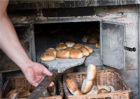 A man sliding bread rolls out of the oven and into wicker baskets Foto de stock - Sin royalties Premium, Código: 659-08906664