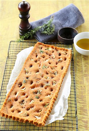 pane all'aglio - Vegan focaccia with dried tomatoes, garlic and herbs on a cooling rack Fotografie stock - Premium Royalty-Free, Codice: 659-08906759