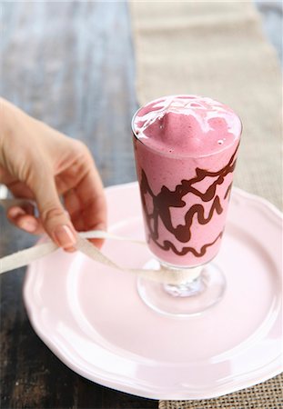 simsearch:659-08897178,k - A raspberry & chocolate smoothie in a glass being decorated with ribbon Stock Photo - Premium Royalty-Free, Code: 659-08906753