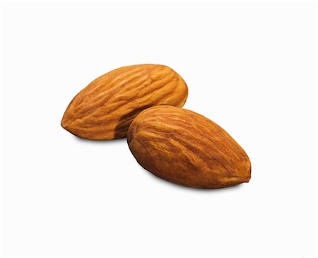Two shelled almonds on a white surface (close-up) Stock Photo - Premium Royalty-Free, Code: 659-08902689