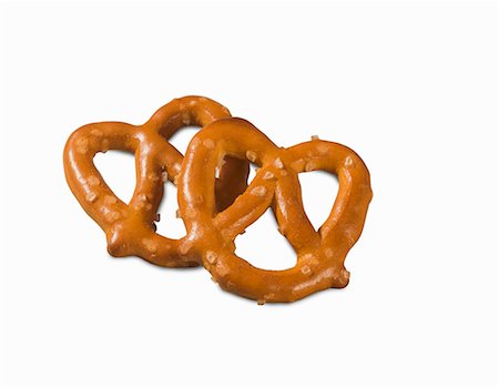 simsearch:659-08902725,k - Two mini salted pretzels on a white surface (close-up) Foto de stock - Sin royalties Premium, Código: 659-08902690