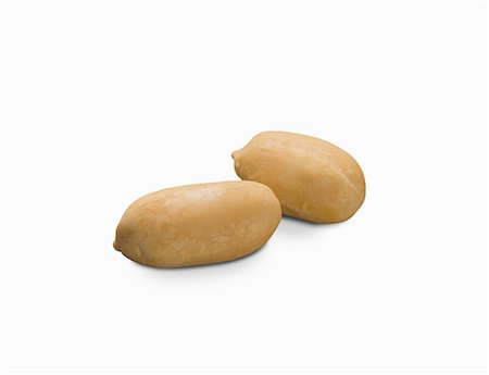 Two shelled peanuts on a white surface (close-up) Stock Photo - Premium Royalty-Free, Code: 659-08902691