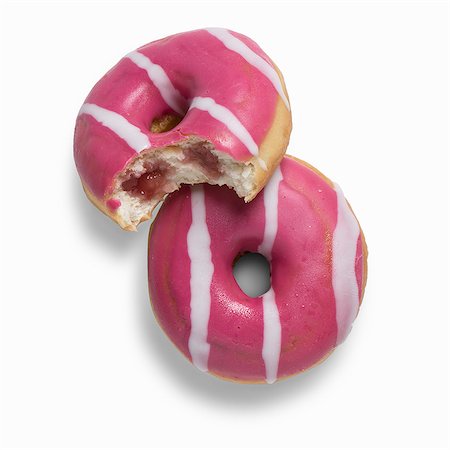 simsearch:659-07739773,k - Two pink strawberry doughnuts filled with strawberry jam, one with a bite taken out Stock Photo - Premium Royalty-Free, Code: 659-08903312