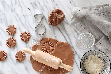 Gluten-free pastry rolled out with a rolling pin with cutters and a bowl of gluten-free flour on a marble surface Foto de stock - Sin royalties Premium, Código: 659-08903890