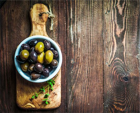 Green and black olives in a dish on a chopping board (seen from above) Stock Photo - Premium Royalty-Free, Code: 659-08939987