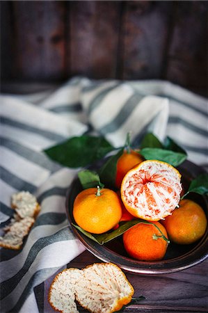 simsearch:659-07610103,k - Mandarins with leaves in a metal bowl on a rustic wooden surface Photographie de stock - Premium Libres de Droits, Code: 659-08940023