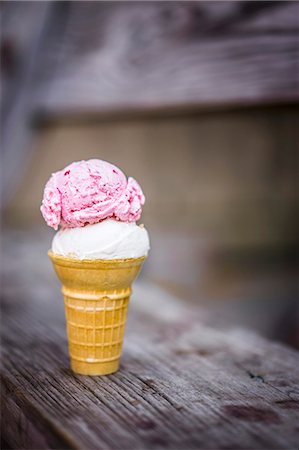 simsearch:659-06494432,k - A scoop of coconut and a scoop of strawberry ice cream in an ice cream cone on a wooden table Stock Photo - Premium Royalty-Free, Code: 659-08940032