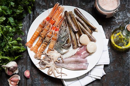 Various types of seafood on a plate with olive oil, herbs and garlic Stock Photo - Premium Royalty-Free, Code: 659-08940068