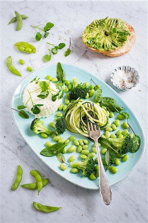 A green salad made of courgette spaghetti, Edamame beans, broccoli, water cress, bloodwort, baby spinach with ricotta, avocado bagel Stock Photo - Premium Royalty-Free, Code: 659-08940072