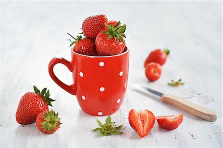 simsearch:659-06153643,k - Fresh strawberries in a cot next to sliced fruit Photographie de stock - Premium Libres de Droits, Code: 659-08940257