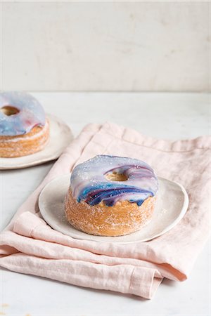 Two galaxy croissant doughnuts with marble glaze on plates Stock Photo - Premium Royalty-Free, Code: 659-09124951