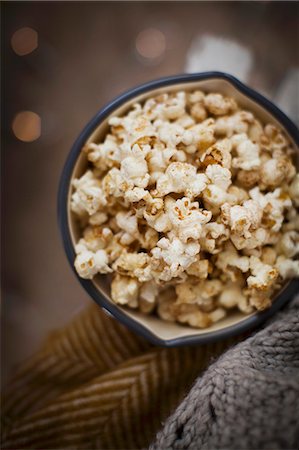 pipoca - Vanilla and cinnamon pop corn in an annamel pan with blankets against a dark background with fairy lights Foto de stock - Royalty Free Premium, Número: 659-09125049