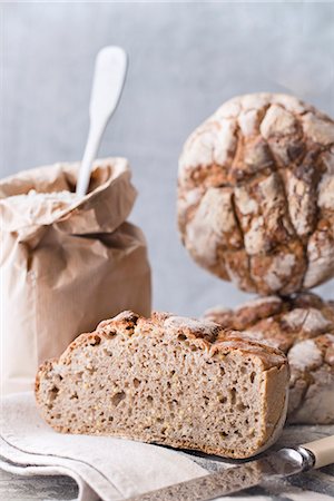 simsearch:659-06903123,k - Homemade sourdough bread on a cloth next to a bag of flour and a knife Photographie de stock - Premium Libres de Droits, Code: 659-09125389
