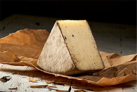 food, dark background - A wedge of pecorino with potash and cinnamon on paper Stock Photo - Premium Royalty-Free, Code: 659-09125477