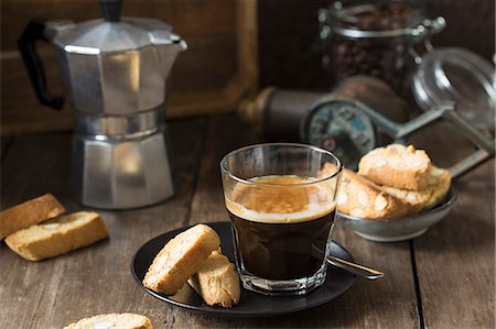 Espresso in a glass and cantuccini with a stove-top coffee maker in the background Stock Photo - Premium Royalty-Free, Code: 659-09125496