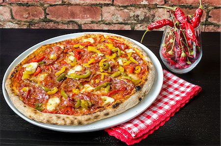 Pizza made with a sourdough base, tomato sauce with oregano and olive oil, mozzarella cheese, green, yellow and red peppers, spicy salami, pepperoni, chorizo Photographie de stock - Premium Libres de Droits, Code: 659-09125765