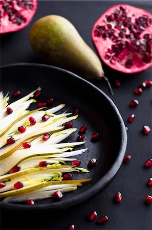 simsearch:659-09125465,k - Pear and endive salad with pomegranate seeds in a black plate on black background Stock Photo - Premium Royalty-Free, Code: 659-09125763