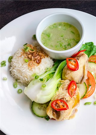 south east asian cooking - Thai chicken thighs with fresh chilly, cucumber and tomato salad, white basmati rice and spring onion broth on a white plate Stock Photo - Premium Royalty-Free, Code: 659-09125787