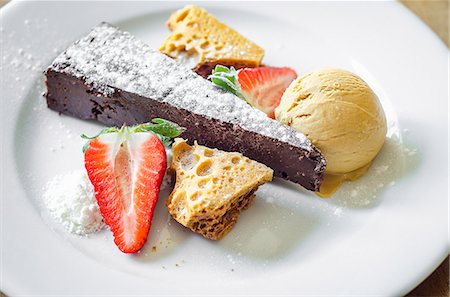 simsearch:659-07598736,k - Moist and rich chocolate and honeycomb cake served with honeycomb, ice cream and fresh strawberries decorated with icing sugar Photographie de stock - Premium Libres de Droits, Code: 659-09125827