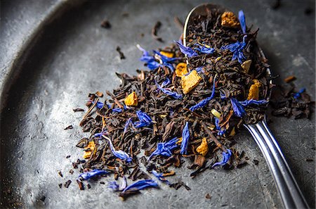 Loose leaf Earl Grey tea with dried citrus peel of lemon, orange and bergamot and blue cornflowers on a dark metal plate and a teaspoon Foto de stock - Royalty Free Premium, Número: 659-09125831