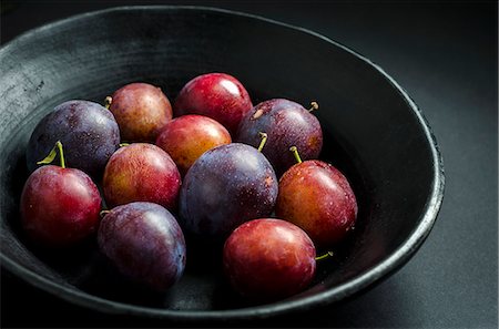 simsearch:659-07959622,k - bowl of fresh purple and red prunes and plums in a black fruit bowl on a black background Stockbilder - Premium RF Lizenzfrei, Bildnummer: 659-09125886