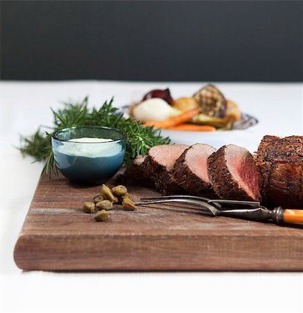 simsearch:659-07028998,k - Rolled roast beef with horseradish sauce, rosemary and capers, roast vegetables in the background Stockbilder - Premium RF Lizenzfrei, Bildnummer: 659-09125928