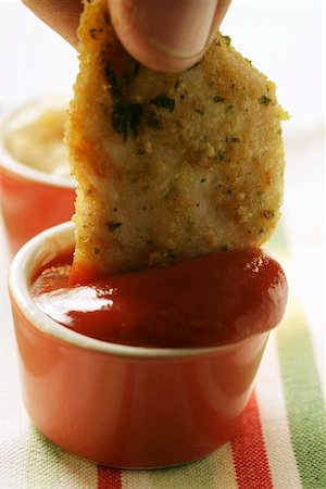 Dipping chicken nugget into ketchup Fotografie stock - Premium Royalty-Free, Codice: 659-01844507