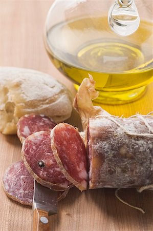 food still life - Italian salami, partly sliced, white bread, olive oil Stock Photo - Premium Royalty-Free, Code: 659-01845853