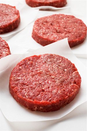 Several raw burgers on paper Stock Photo - Premium Royalty-Free, Code: 659-01846035