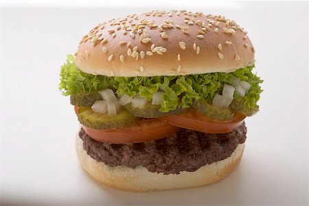 simsearch:659-01846088,k - Hamburger with tomato, gherkin, onion and lettuce Foto de stock - Sin royalties Premium, Código: 659-01846051