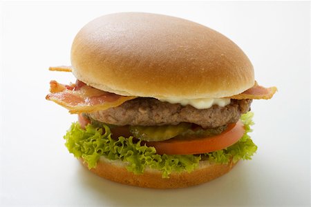 simsearch:659-01846088,k - Hamburger with bacon, mayonnaise, gherkins, tomato, lettuce Foto de stock - Sin royalties Premium, Código: 659-01846082