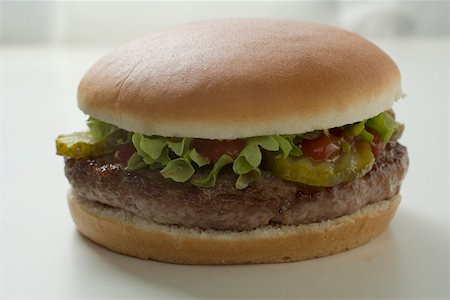 simsearch:659-01846088,k - Hamburger with gherkin, lettuce and ketchup Foto de stock - Sin royalties Premium, Código: 659-01846113