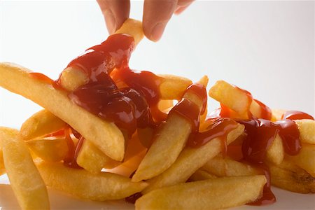 Hand taking chips with ketchup Stock Photo - Premium Royalty-Free, Code: 659-01846324