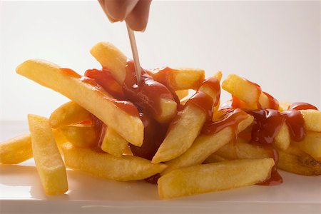 simsearch:659-06494742,k - Hand taking chips with ketchup with wooden stick Foto de stock - Sin royalties Premium, Código: 659-01846326