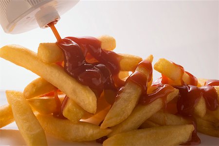 Squirting ketchup from a bottle onto chips Stock Photo - Premium Royalty-Free, Code: 659-01846323