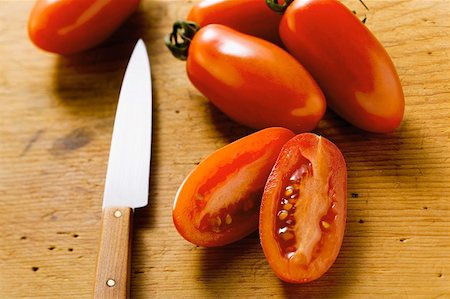 Five 'date' tomatoes on wooden background, one halved Stock Photo - Premium Royalty-Free, Code: 659-01846793