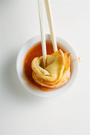 simsearch:659-03527672,k - Dipping a deep-fried wonton in sweet and sour sauce Stock Photo - Premium Royalty-Free, Code: 659-01847264