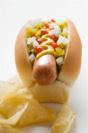 Hot dog with relish, mustard, ketchup, onions and crisps Stock Photo - Premium Royalty-Free, Code: 659-01847325